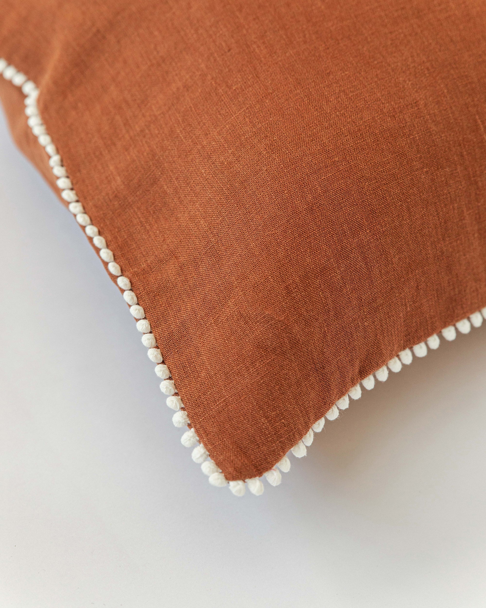 Cushion cover with pom poms in Cinnamon